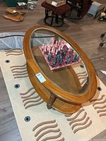 Full view of oval wood coffee table with glass top and cane shelf