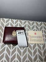 Closed maroon case with Canadian coat of arms and accompanying information card