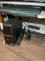 HP desktop tower under desk on wheeled cart with keyboard visible