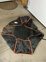 Full view of black quilted dog seat cover with orange trim