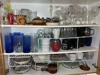 Overview of cupboard showing glassware, mugs, ramekins, plates and covered dishes