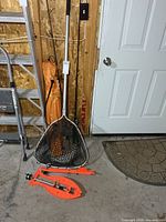 Landing net, orange ice-fishing tip-ups, chair bag partially visible