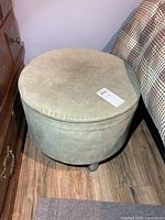 Top view of the round footstool showing upholstery and size tag