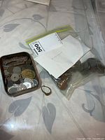 Bag and tin with coins, ring placed nearby