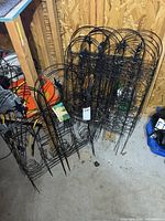 Stacked black metal fence panels and trellis leaning against wall