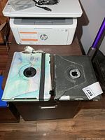 Two iPads in cases on cabinet next to HP printer