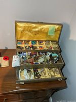 Wood jewelry box open showing compartments and drawer filled with assorted jewelry