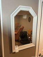 Front view of white framed mirror hanging on wall