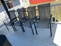 Four grey sling patio chairs on deck