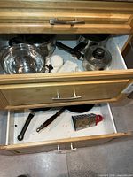 Drawer with pots, colander, lids, frying pans, grater