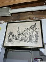 Full view of framed street scene print hanging on wall