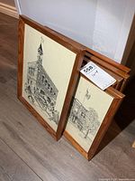 Stack of framed prints showing wood frames and artwork edges