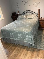 Full view of queen bed with headboard, mattress, box spring and bedding