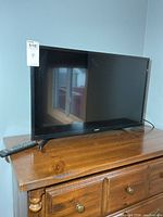 Front view of Samsung 32-inch TV with remote on stand