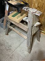 pair of wooden sawhorses with leaf bags and paint tray visible