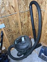 Shop-Vac wet/dry vacuum standing in garage with hose attached