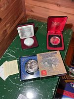 Three cased Canadian silver dollars: Henry Kelsey coin, unidentified coin in burgundy case, Golden Jubilee coin in blue box