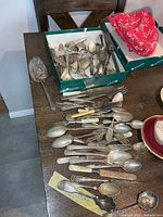 Overview of table and box showing quantity and variety of tarnished cutlery