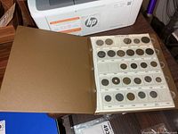 Open binder showing page of coin pockets with coins inside