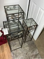 Front view of the three nesting metal and glass pedestal tables showing sizes and leaf motif