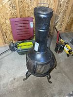 Full view of black steel chiminea standing on cast iron legs