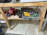 Workbench shelf holding sander, spotlight, cords and bin of gloves