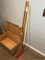 Three wooden hockey sticks leaning against wall: Louisville Slugger Wrangler, CCM, white/red autographed stick