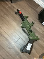Full view of green plastic Johnny Seven rifle on floor