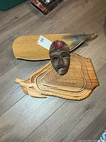 Wooden mask, boat-shaped tray, nested bowls grouped on floor