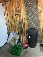 Group of yard tools, snow scoop, broom, rakes, lattice and garbage can