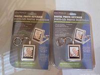 Front view of both packaged OneWorld digital photo keychains