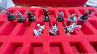 Tray view of 11 metal miniatures in red foam