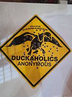 Front view of yellow Duck Commander sign with text and graphics