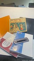 Lot overview showing children’s book, binders, sealed ruled paper packs, hole punch
