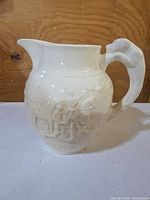 Full left side view showing spout, handle and relief figures