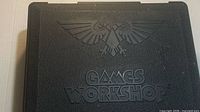 Front of black Games Workshop carrying case showing embossed logo and Aquila
