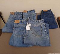 Stack of five Levi’s jeans showing back pockets, leather patches, red tabs and overall color range