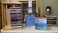 Overview showing stacked CDs, box sets, empty jewel cases and two wooden racks