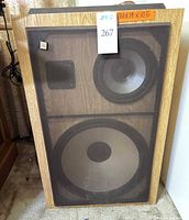 Front view of one BSR DR-1550L speaker showing grille, wood veneer, and size reference tag
