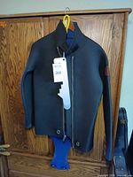 Front view of black neoprene wetsuit jacket with blue interior and attached lower section