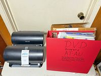 Two black disc organizers and red binder labeled DVD inserts