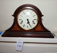 Front view of Howard Miller tambour mantel clock with dial, bezel and key visible