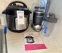 Instant Pot Duo Plus cooker, NutriBullet blender base, two cups, manual visible
