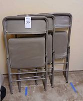 Three folded metal chairs showing backs and legs