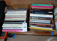 Two cardboard boxes filled with stacked music books showing spines with titles such as Classic Piano Rags, The Real Rock Book Vol II, Jazz Fakebook, Finishing the Hat
