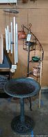 Full view of bird bath, wind chime, plant stand with pots