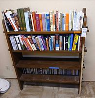 Front view of brown wooden bookcase holding books and CDs