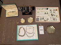 Overall lot showing boxed bracelet, bracelet stand with bracelets, pink tray of small jewelry pieces, necklaces, trays
