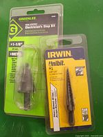 Front view of both Greenlee and Irwin step drill bits in blister packaging