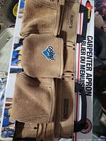 Front view of boxed Kuny's / Benchmark leather-suede carpenter apron tool belt showing pouches and packaging